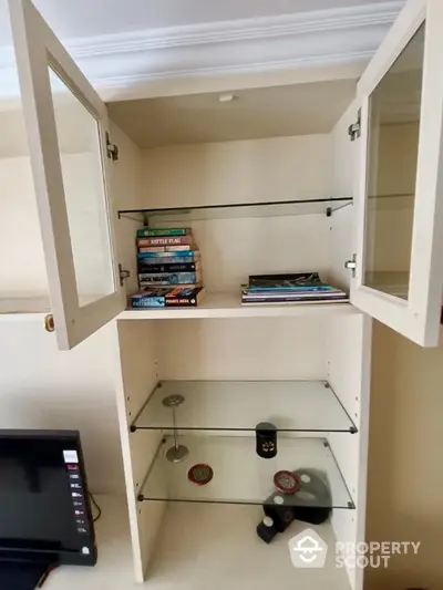 Charming built-in shelving unit with glass doors and shelves, perfect for displaying books and decor in a cozy living space.