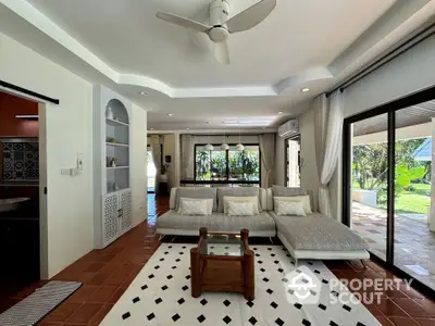 Spacious living room with modern decor and garden view, featuring large windows and elegant furnishings.