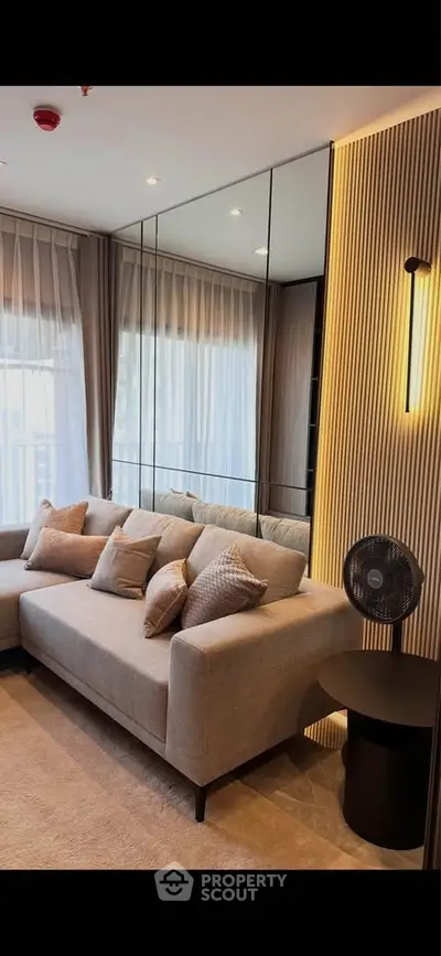 Elegant living room with modern sofa, mirrored wall, and stylish lighting