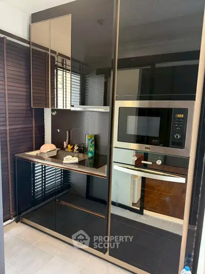 Modern kitchen with sleek black cabinetry and built-in oven, perfect for contemporary living.