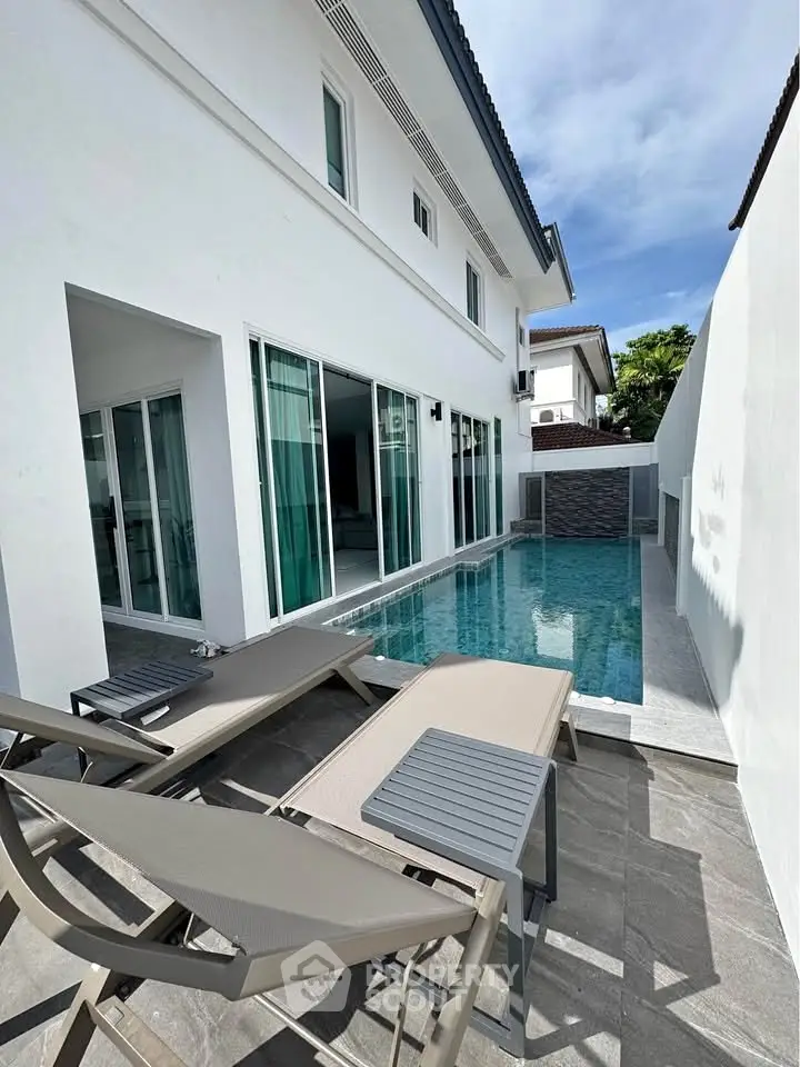 Luxurious modern home with private pool and sun loungers, perfect for relaxation and entertainment.