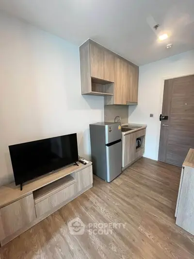 Modern compact living room with kitchenette and wooden flooring