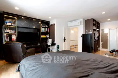 Spacious bedroom with modern decor and built-in shelving, featuring a cozy seating area and sleek air conditioning unit.