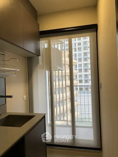 Modern kitchen with sleek cabinetry and balcony view in urban apartment