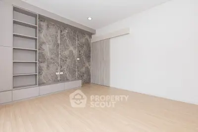 Spacious modern living room with elegant built-in shelving and sleek wooden flooring.