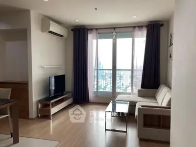 Modern living room with city view, featuring sleek furniture and large windows.