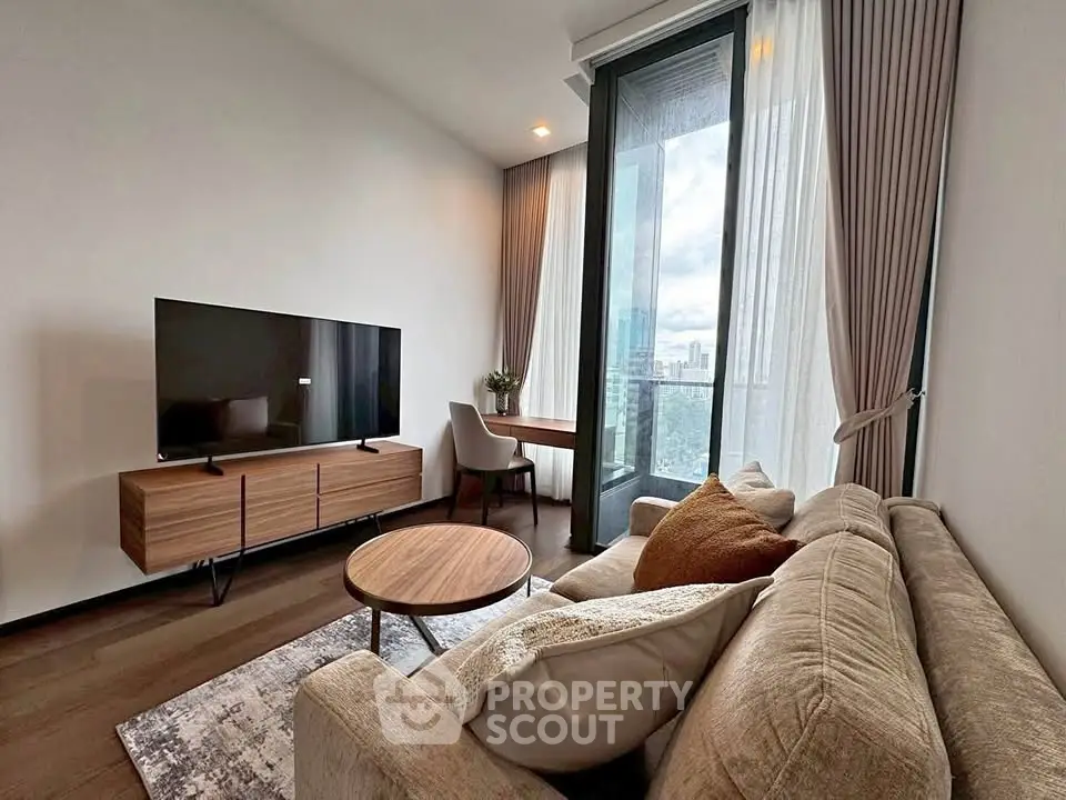 Modern living room with large TV, cozy sofa, and city view from balcony.