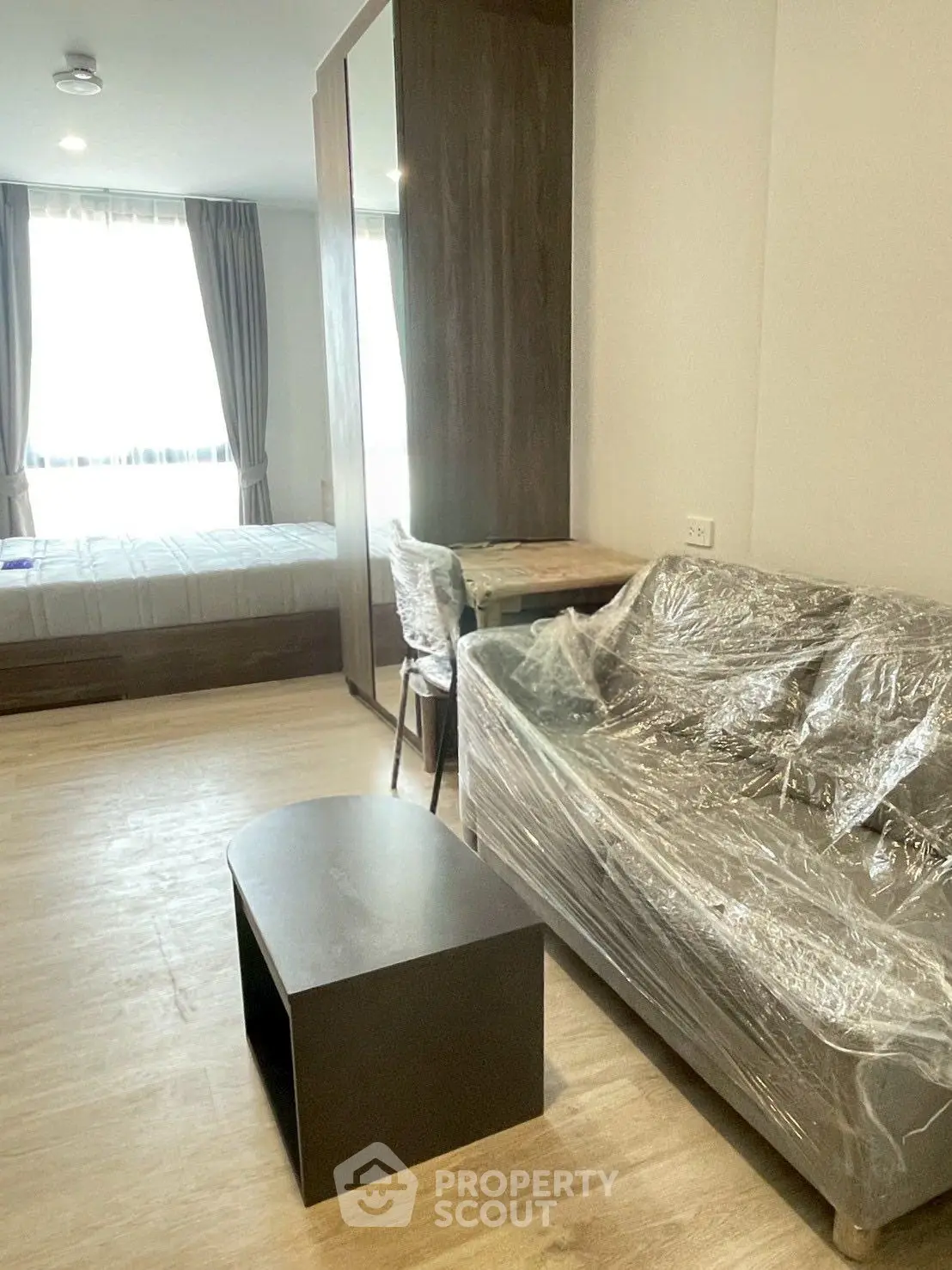 Modern studio apartment with natural light, featuring a cozy living area and bedroom with stylish furnishings.