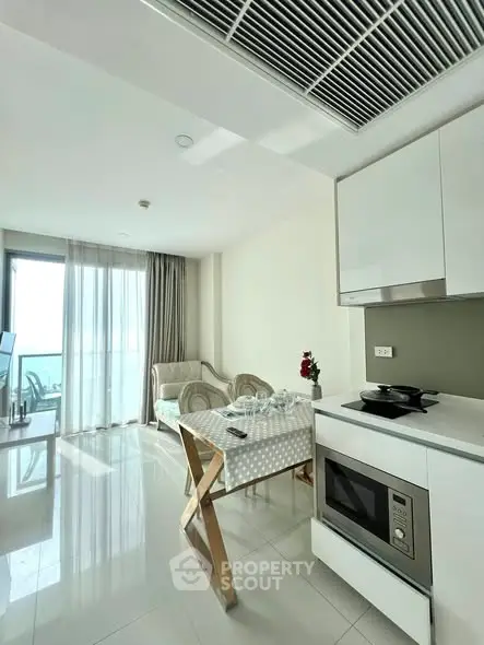 Modern open-plan living room with kitchen, featuring sleek appliances and a cozy seating area.