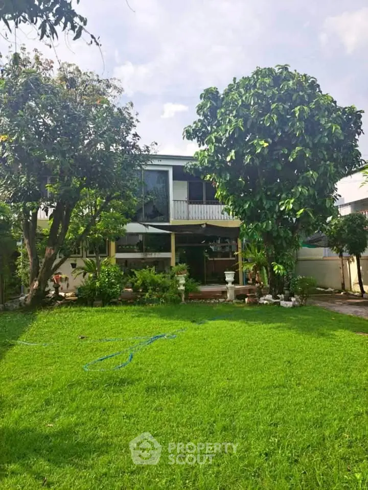 Charming two-story home with lush garden and mature trees, perfect for family living and outdoor enjoyment.