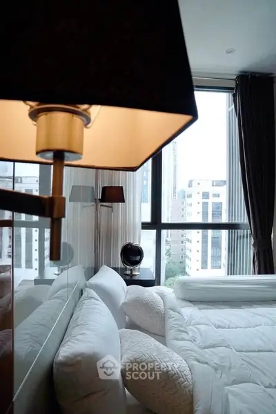 Luxurious bedroom with large windows offering stunning city views, elegant decor, and plush bedding.