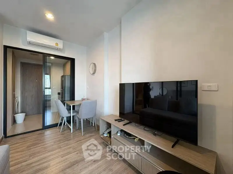 Modern living room with sleek design, featuring a large TV and stylish dining area, perfect for urban living.