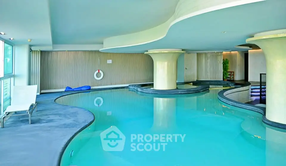 Luxurious indoor swimming pool with modern design and elegant pillars in a high-end residential building.