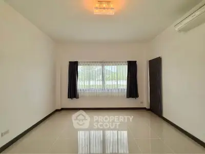 Spacious empty room with large window and air conditioning, perfect for customization.