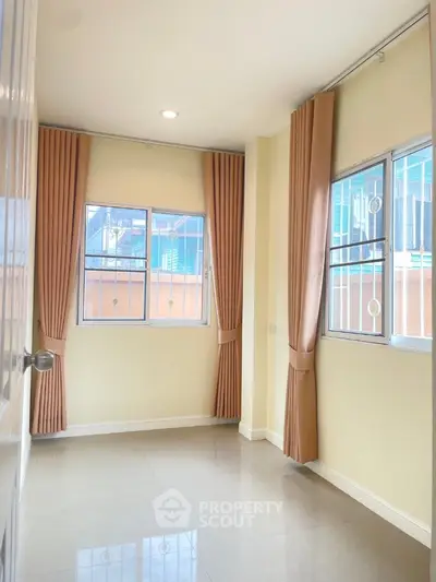 Bright room with large windows and beige curtains, ideal for versatile use in modern home.
