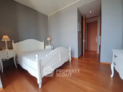 Spacious bedroom with elegant white furniture and wooden flooring