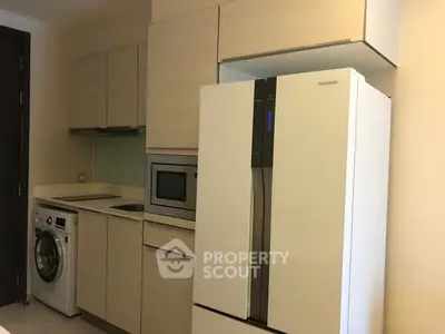 Modern kitchen with sleek appliances and washing machine in compact layout.