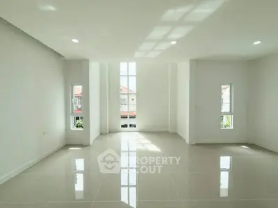 Spacious and bright living room with large windows and glossy tiled floors.
