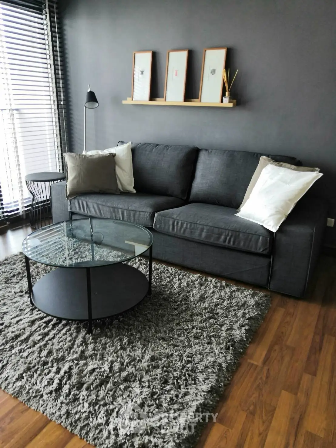 Modern living room with gray sofa, glass coffee table, and stylish decor.