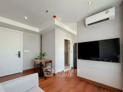 Modern living room with sleek TV and air conditioning, featuring wooden flooring and a cozy dining area.