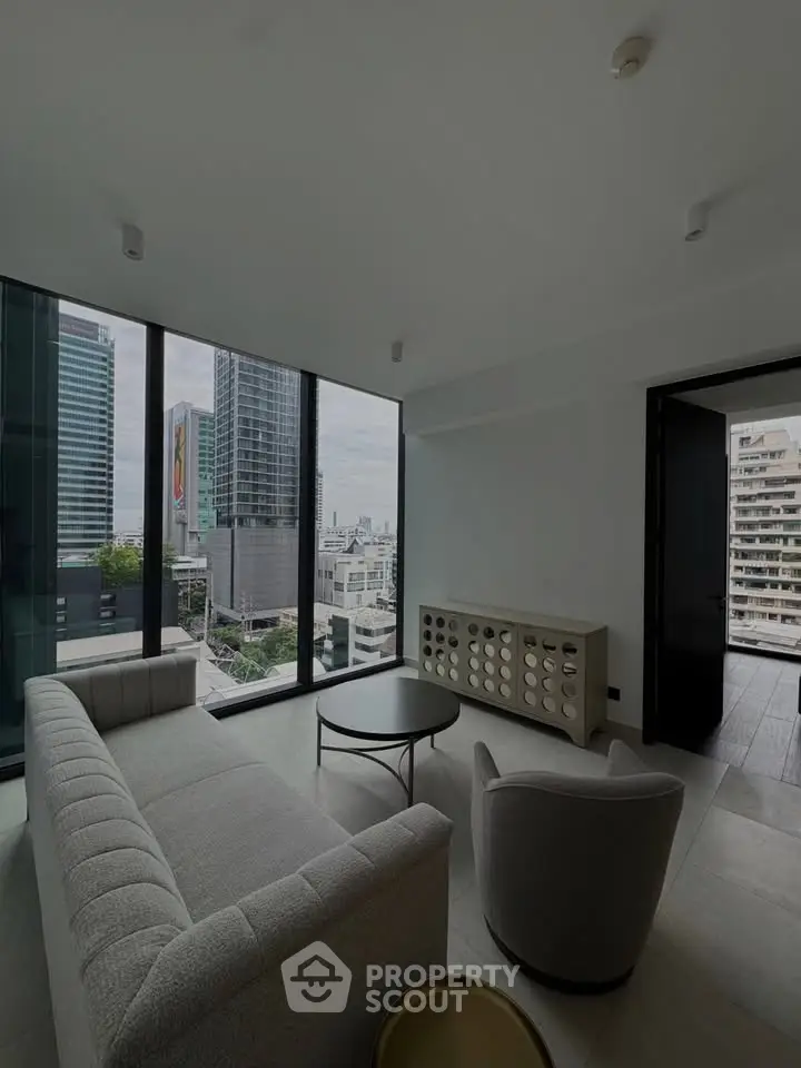 Modern living room with panoramic city view, featuring sleek furniture and floor-to-ceiling windows.