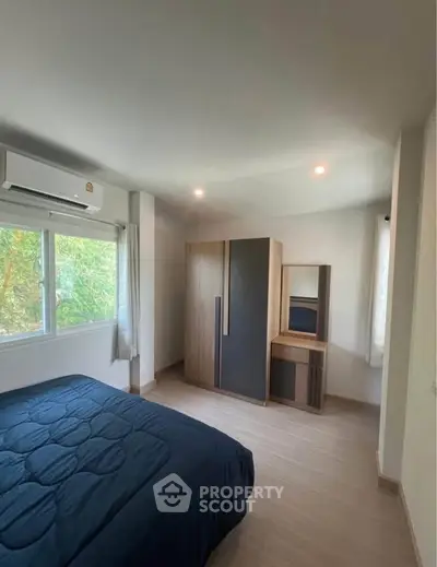 Cozy bedroom with modern wardrobe and large window offering natural light.
