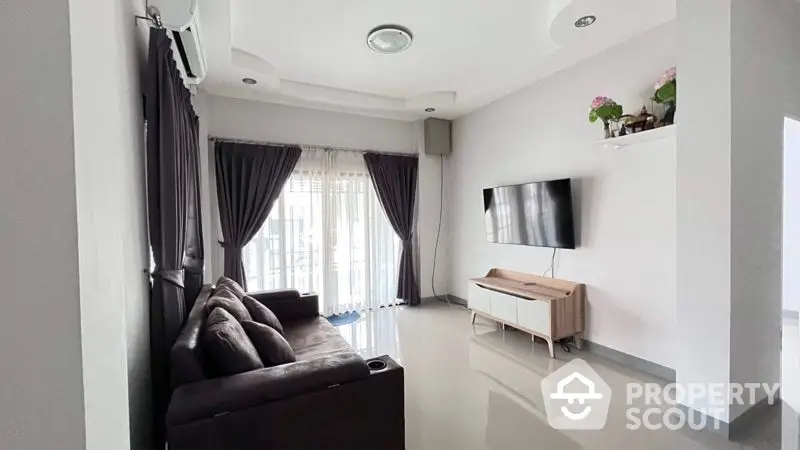 Spacious modern living room with glossy white tiles, elegant dark curtains, and sleek furniture, leading to a sunlit balcony.