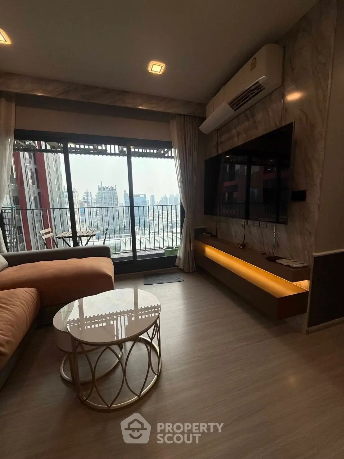 Modern living room with city view, featuring stylish furniture and large windows for natural light.