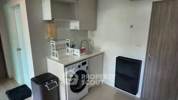 Compact laundry area with washing machine and sink in modern apartment
