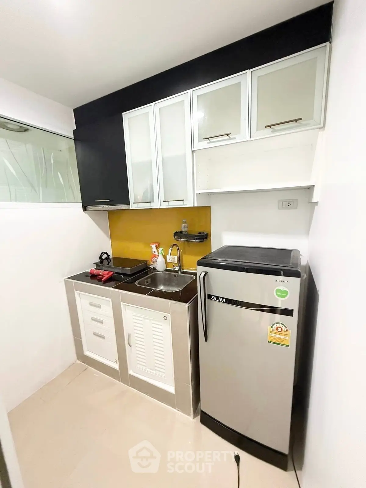 Compact modern kitchen with sleek cabinets and stainless steel appliances in a cozy apartment.