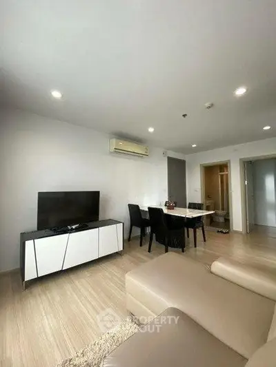 Modern living room with sleek furniture and dining area in open layout apartment.