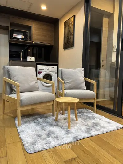 Cozy modern living area with washing machine and stylish furniture in open layout.