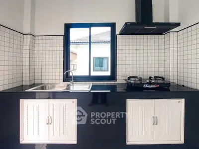 Modern kitchen with sleek black countertops and gas stove, featuring a minimalist design.