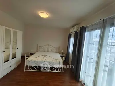 Spacious bedroom with elegant bed and large windows offering natural light