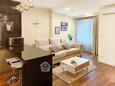 Modern living room with stylish decor and open kitchen layout, featuring cozy sofa and elegant lighting.