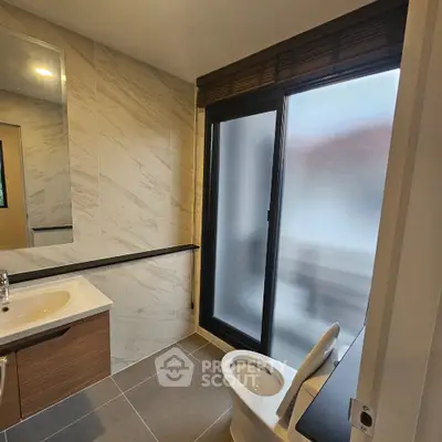 Modern bathroom with sleek design, featuring a large frosted window and contemporary fixtures.