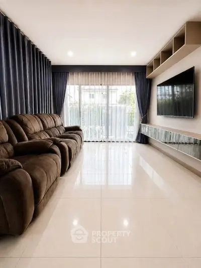 Spacious modern living room with plush seating and large TV, perfect for relaxation and entertainment.