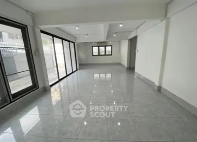 Spacious open-plan living room with large windows and glossy tiled floors, perfect for modern living.
