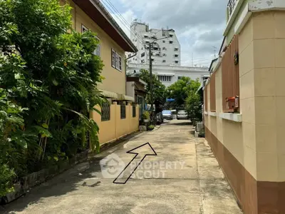 Charming residential alley with lush greenery and urban backdrop, perfect for serene living.