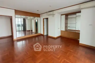 Spacious empty living room with wooden flooring and mirrored wall, perfect for customization.