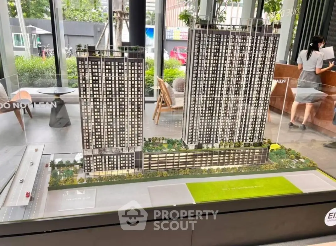 Modern architectural model of high-rise residential complex with lush landscaping.