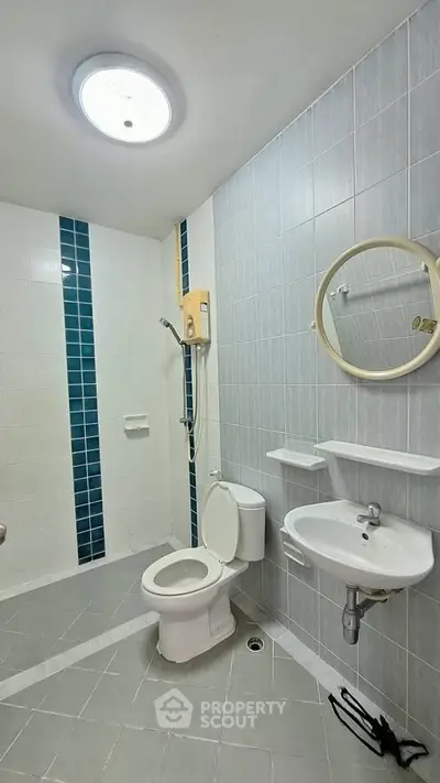 Modern bathroom with sleek design, featuring a shower, toilet, and sink in a tiled setting.