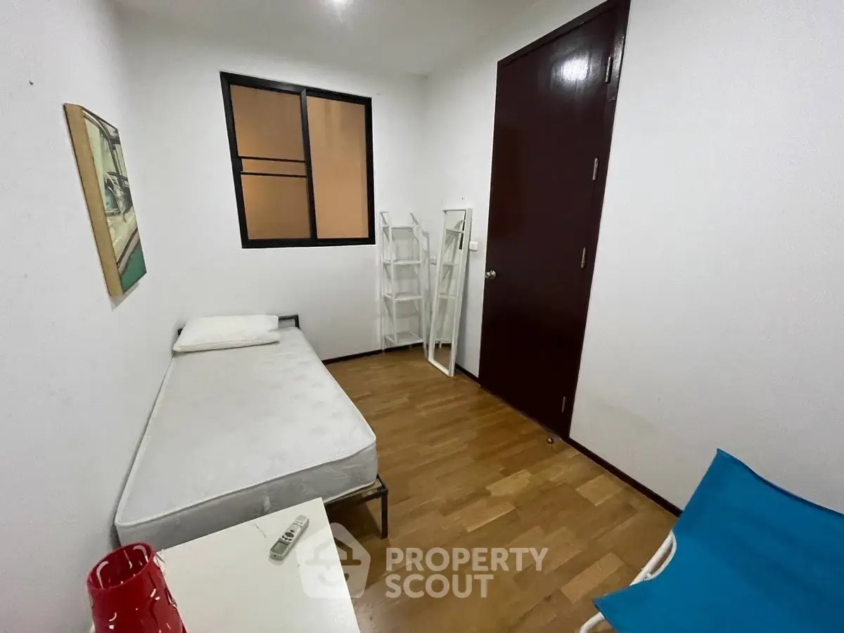 Cozy minimalist bedroom with single bed and wooden flooring, ideal for compact living spaces.