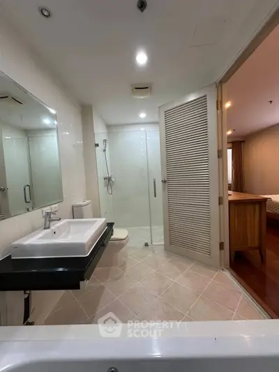 Modern bathroom with glass shower and sleek sink in a stylish apartment.