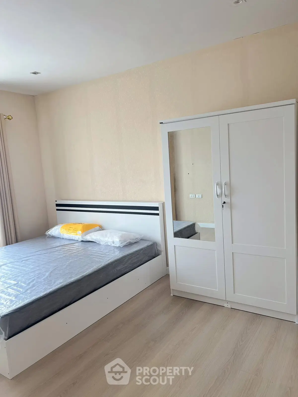 Modern bedroom with sleek white furniture and cozy bed in a bright apartment.