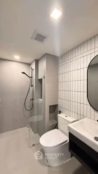 Modern bathroom with sleek design, featuring a glass shower enclosure and contemporary fixtures.