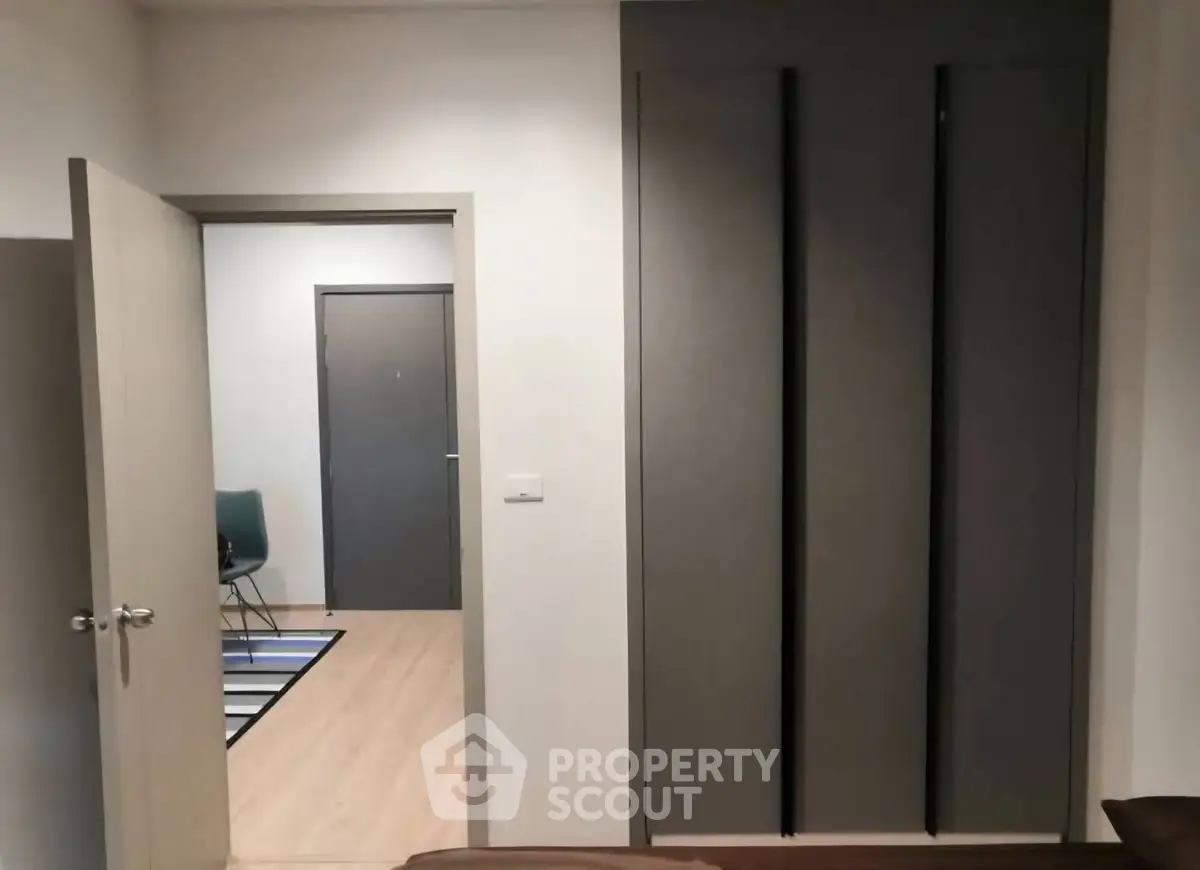 Modern apartment interior with sleek wardrobe and open door to hallway.