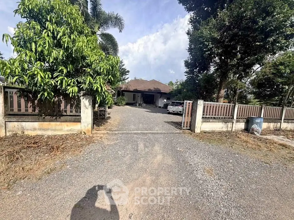 Charming single-story home with spacious driveway and lush greenery, perfect for serene living.