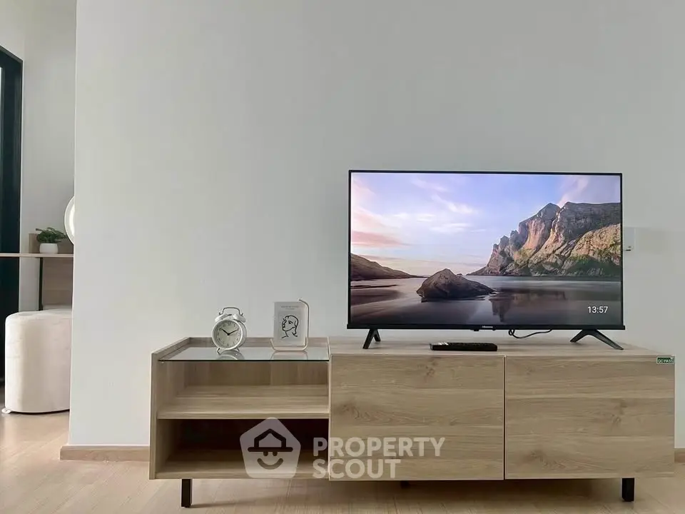 Modern living room with sleek wooden TV stand and flat-screen TV displaying scenic view.