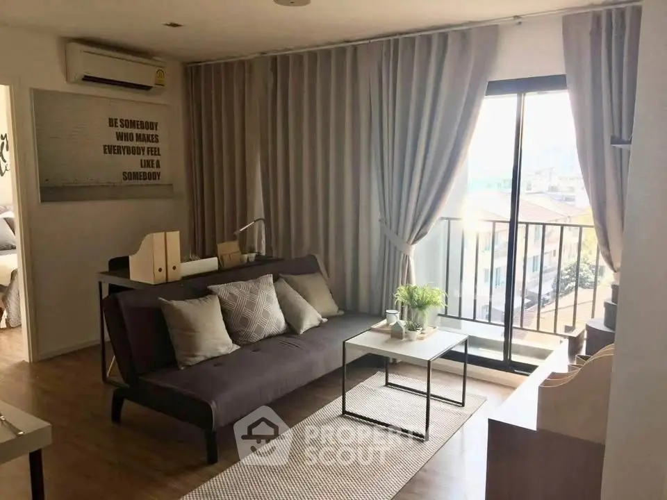 Modern living room with balcony view, stylish decor, and ample natural light in urban apartment.